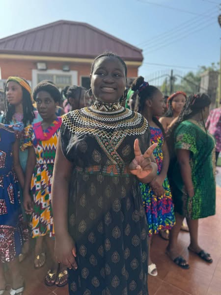 Student in traditional attire making peace sign
