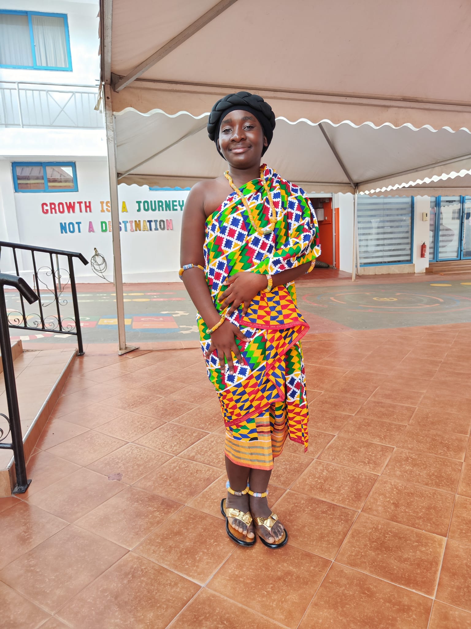 Student in vibrant kente patterns with black head wrap