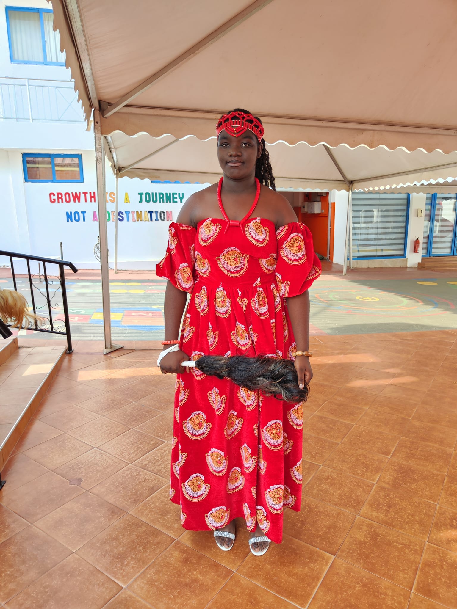 Student in red patterned dress with head wrap